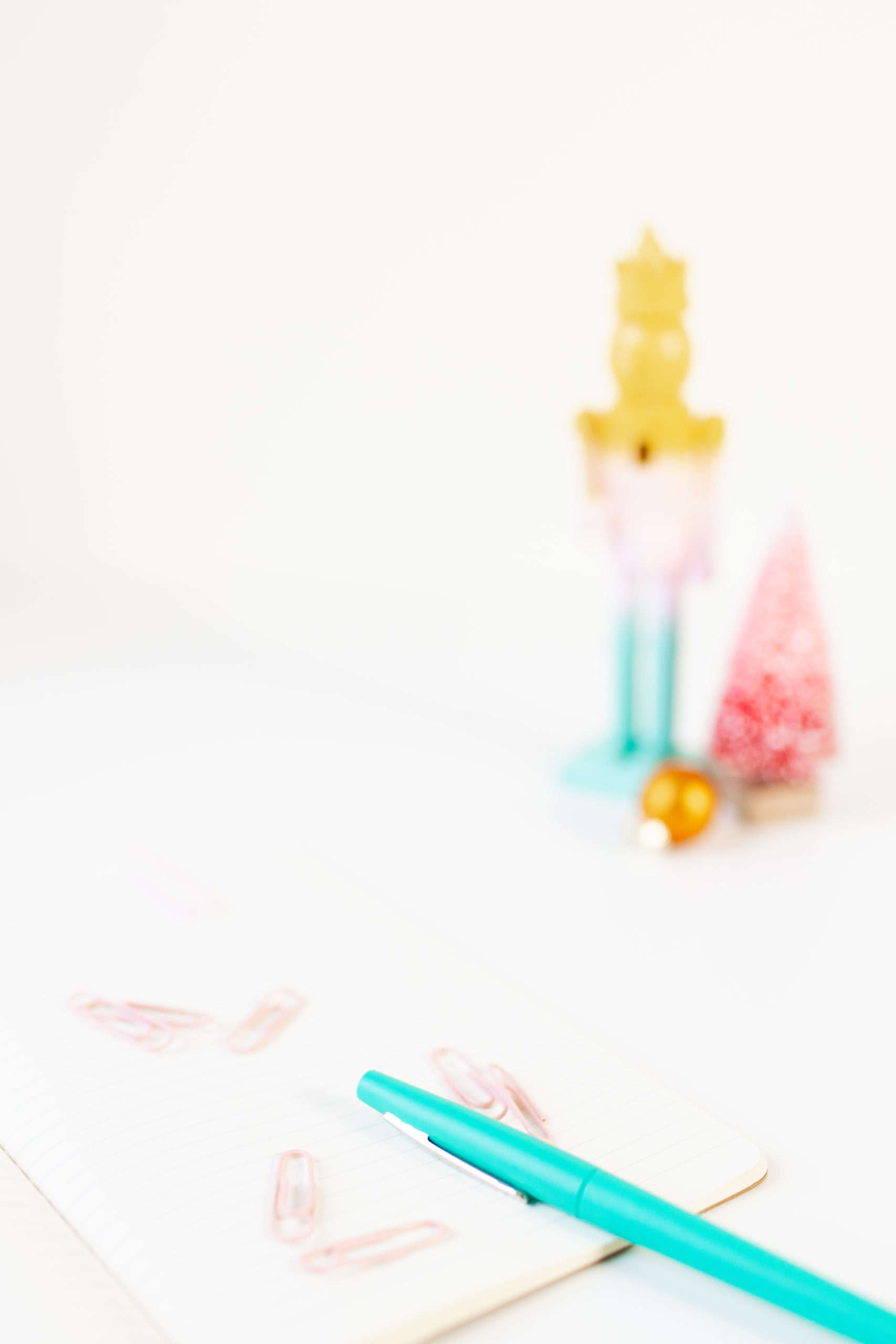 notepad and paper clips in the foreground with a colorful nutcracker in the background